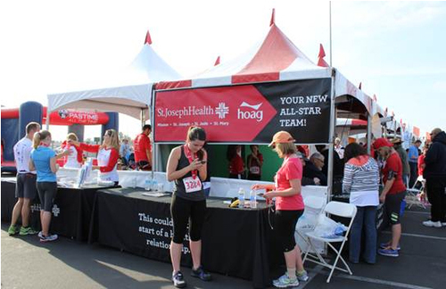 Marathon event staging area with 2 participates in front of the St Joseph Health Sponsorship tent