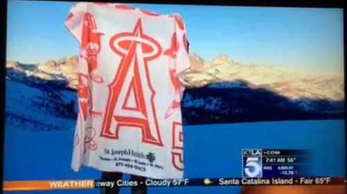 Outdoor mountain scene with an MLB Angels stadium giveaway towel from St. Joseph Health during KTLA news broadcast