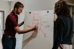 Guys writing on a white board